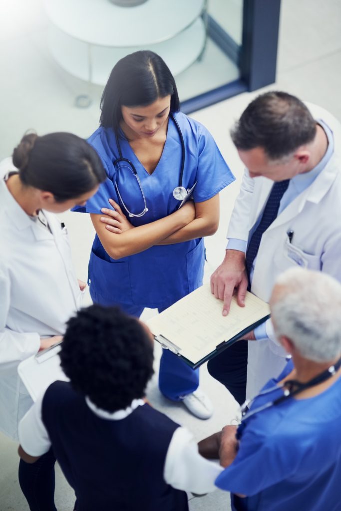 Overhead image of medical professionals in a circle looking at a document